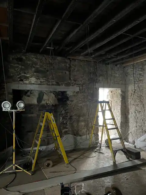 Stripped-out stone room with work lights and stepladders
